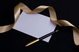 carte blanche stylo noir or ruban doré fond noir
